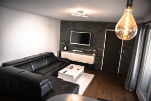 Una sala de estar con un sofá negro y un televisor. en F2 Vaires sur marne, en Vaires-sur-Marne