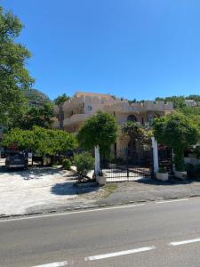 a house with a fence and trees in front of a street at Violit Apartments&Restaurant in Sutomore