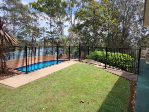 a black fence with a pool in a yard at Motel Miramar in Nambucca Heads