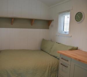 a small bedroom with a bed and a clock on the wall at Corriemuckloch Unique Huts in Dunkeld