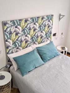a bed with blue pillows and a floral headboard at Vivienda con Parking incluido - Zona Van Dyck in Salamanca