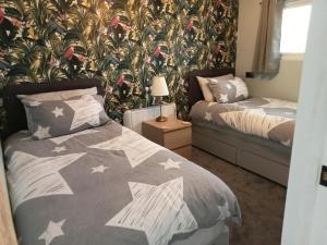 a bedroom with two beds and a wall with plants at 11 Headwards Retreat in Great Yarmouth