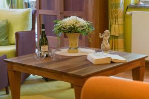 a table with a vase of flowers and a bottle of wine at Villa Charlotte App_13 in Heringsdorf