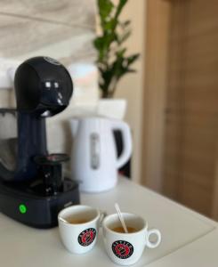 two cups of coffee on a counter next to a coffee maker at Apartman Gold lux in Surčin