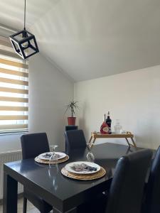 a dining room with a black table and chairs at Apartman Gold lux in Surčin