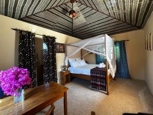 a bedroom with a canopy bed and a table at Mariama Lodge in Mbodiène