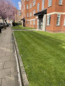 a green lawn in front of a brick building at Impeccable 2-Bed Apartment in London in London