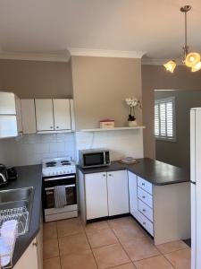 kuchnia z białymi szafkami i czarnym blatem w obiekcie Family friendly Katoomba Cottage w mieście Katoomba