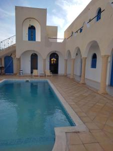 Villa Ulysse Djerba في ميدون: مبنى كبير أمامه مسبح