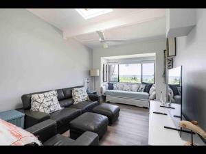 ein Wohnzimmer mit Sofa und Fernseher in der Unterkunft SeaRoos by the Seashore Beach Cottage in Durras