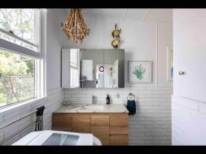 ein weißes Badezimmer mit Waschbecken und Spiegel in der Unterkunft SeaRoos by the Seashore Beach Cottage in Durras + 63 Fotos
