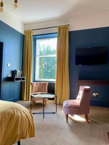 um quarto com uma cama e uma cadeira e uma televisão em The Pines Guest House em Elgin