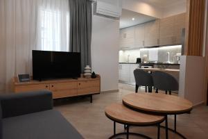 un soggiorno con TV, tavolo e sedie di Mouson House Luxury Apartments a Kavala