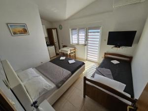 two beds in a small room with a television at Apartment Vesna in Podaca
