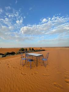 Mustapha Camp Merzouga في مرزوقة: طاولة وكراسي في وسط الصحراء