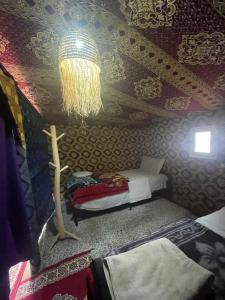 Zimmer mit einem Bett und einer Decke mit einem Kronleuchter in der Unterkunft Mustapha Camp Merzouga in Merzouga