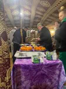 a group of people standing around a table with oranges at Mustapha Camp Merzouga in Merzouga
