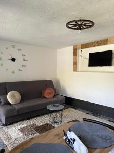 uma sala de estar com um sofá e um relógio na parede em Apartman Azra em Kulen Vakuf