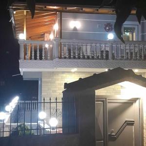 une maison avec un balcon éclairé la nuit dans l'établissement Vesi apartment, à Gjirokastër