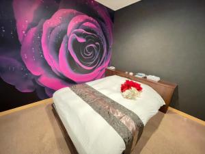 ホテル レディ في Kōtōdaitōri: غرفة نوم بسرير مع وردة على الحائط