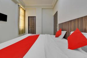 a red stripe on a white bed in a room at Flagship Hotel The Gold in Jaipur