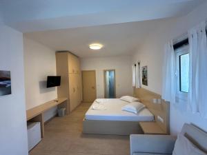 a white bedroom with a bed and a desk at Dima Vista in Dhërmi +24 photos