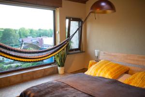 1 dormitorio con hamaca frente a una ventana en Schlossberg Apartments & Garten in der Natur & unweit vom "Thüringer Meer", en Unterwellenborn