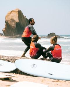un gruppo di tre persone seduti sulla spiaggia con tavole da surf di Ocean Beach House a Torres Vedras