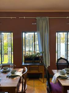 a dining room with two tables and windows at Greyton Toad Hall Guesthouse - no load shedding in Greyton