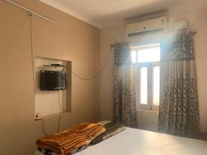 a bedroom with a bed and a tv and a window at MOON HAVELI in Bikaner