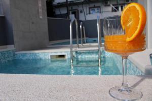 a glass of orange juice sitting on a table next to a pool at Villa Melassy in Makarska
