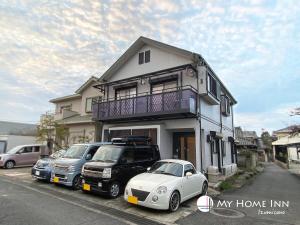 una macchina bianca parcheggiata di fronte a una casa di My Home Inn Izumisano a Izumisano