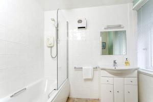 a white bathroom with a sink and a shower at April Cottage in Minehead +16 photos