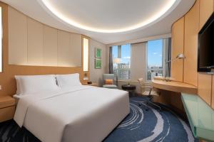 a bedroom with a large white bed and a desk at Crowne Plaza Shenzhen Futian, Near by Futian Station and Coco Park, Outdoor Heated Pool in Shenzhen