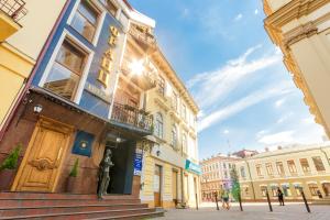 Un edificio con una statua davanti di Franz Hotel&Restaurant a Ivano-Frankivsʼk