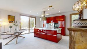 een keuken met rode kasten en een eettafel bij Maison Olivier in Veigy-Foncenex