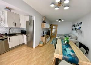 a kitchen and living room with a wooden table in a room at APARTAMENTO CASA PLAYA in Boiro