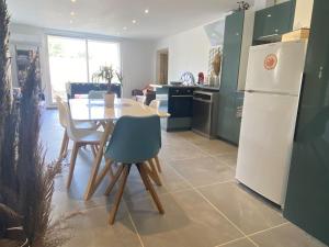 a kitchen with a table and a white refrigerator at REZ de jardin moderne 4 chambres 8 personnes jardinet in Bagnols-sur-Cèze