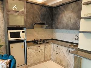 a kitchen with a refrigerator and a microwave at Sandal suite by Mulberry Homestays in Noida