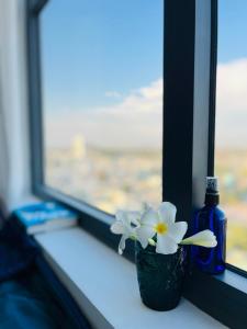 um vaso com flores brancas sentado no peitoril da janela em Livahome - BEE Lux homestay Di An em Dĩ An