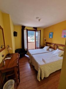 a hotel room with two beds and a desk and a window at Hotel Virginia R.H. in Vinuesa