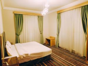 a hotel room with a bed and green curtains at Alhamra Park hotel in Jeddah