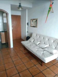 a white couch in a living room with a kite on the wall at Studio em Santos Kitnet in Santos +7 photos