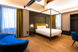 een slaapkamer met een hemelbed en een blauwe bank bij Hotel Touring in Bologna