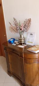 un jarrón de flores sobre un armario de madera en F.A.M. ROOMS, en Ciampino