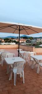 a group of white tables and chairs with an umbrella at F.A.M. ROOMS in Ciampino