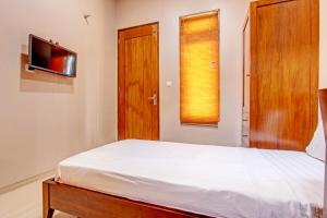 Schlafzimmer mit einem Bett und einem Flachbild-TV in der Unterkunft OYO Life 93497 Griya Kost Rr in Salatiga