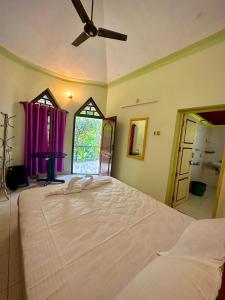 1 dormitorio con 1 cama grande y ventilador de techo en Rams Gratitude Inn, en Varkala