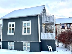 a black house with a chair in the snow at Day Dream - Vesturgata 5a Luxury Apartment in Reykjavík