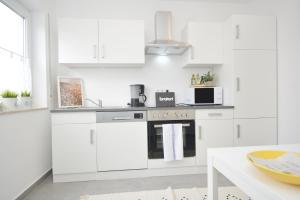 a white kitchen with white cabinets and a table at RT02-FW Wohnung in Schwanstetten in Schwanstetten